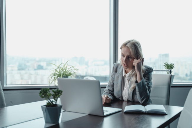 Mujer utilizando un sistema de videoconferencia para empresas mientras mantiene una reunión laboral