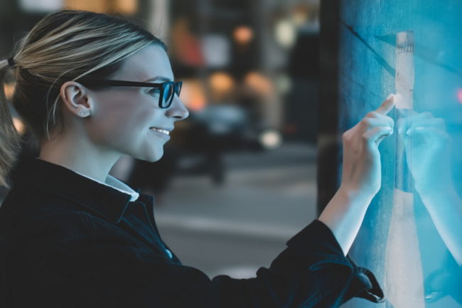 Mujer interactuando con una pantalla digital dentro de un establecimiento.