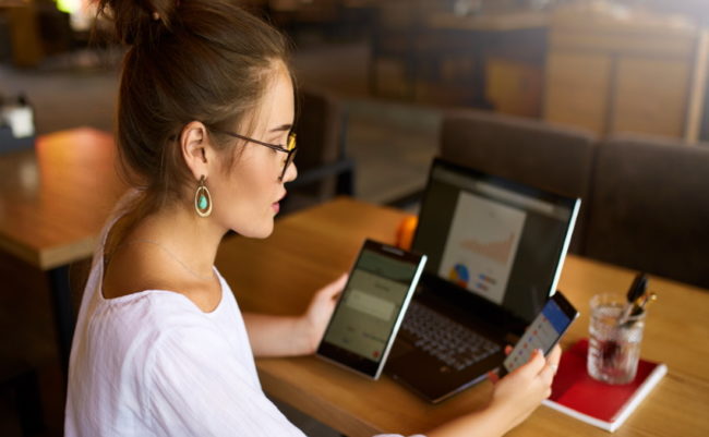 Mujer mirando las pantallas de una tablet, un ordenador portátil y un teléfono.