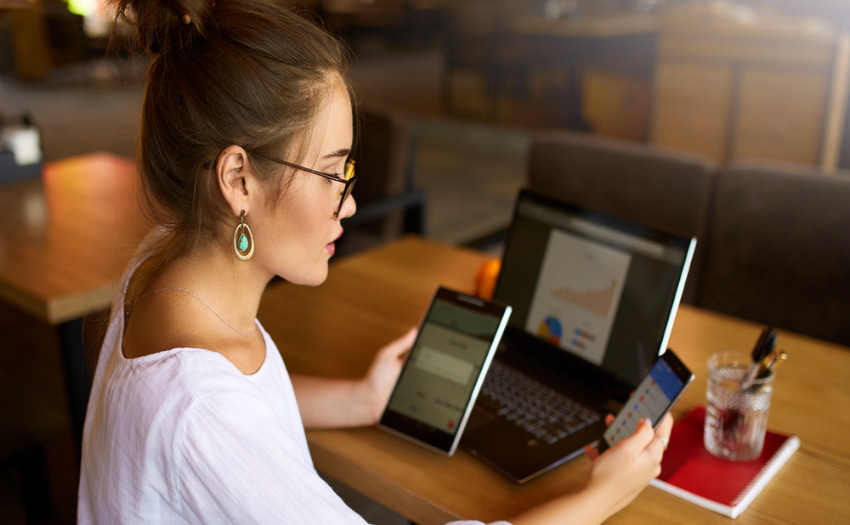 Service Mount Device (SMD) Mujer mirando las pantallas de una tablet, un ordenador portátil y un teléfono.