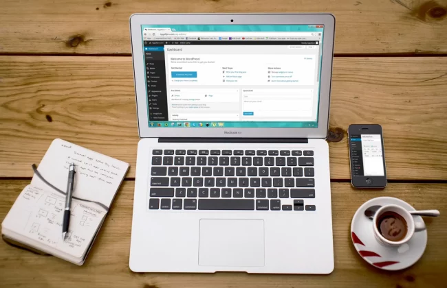 software-de-señalización-digital Mesa con ordenador, libreta, movil y café, mostrandose un cms