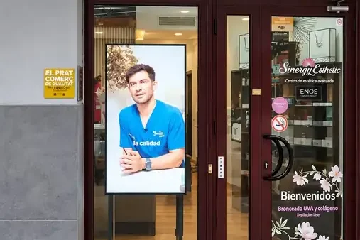 Pantalla profesional vertical integrada en el escaparate de Sinergy Esthetic en El Prat de Llobregat